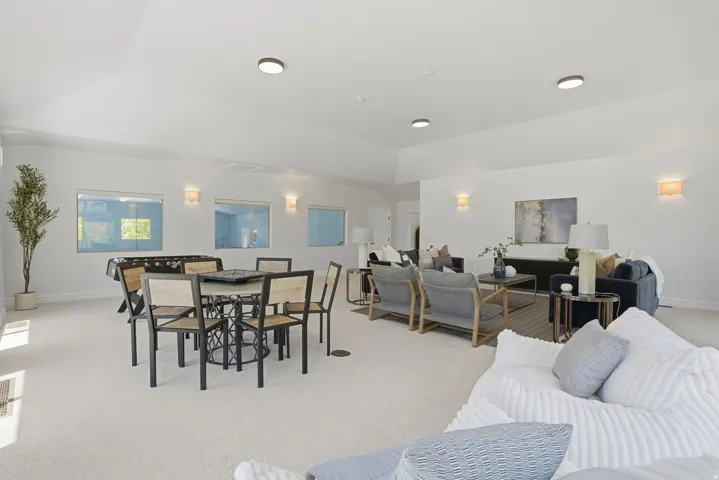 Spacious multi-purpose room featuring neutral carpeting, recessed lighting, and wall sconces