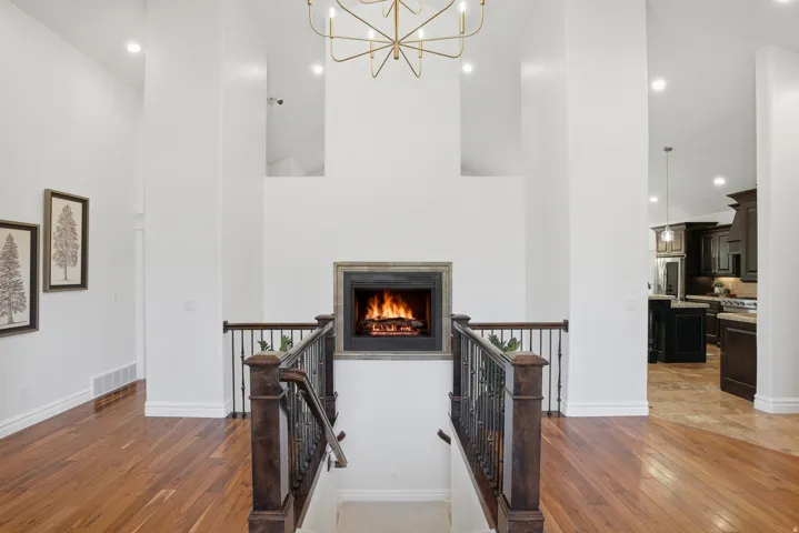 Grand entryway featuring a fireplace with a stone surround, hardwood flooring, and a wrought iron staircase with wood newel posts