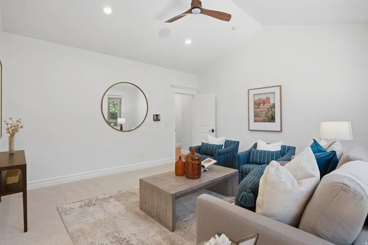 Spacious living area featuring a vaulted ceiling with a modern ceiling fan, recessed lighting, and light-toned carpeting