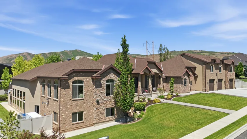 Stately residence featuring a multi-tone brick and stone facade, a multi-car garage, and manicured landscaping