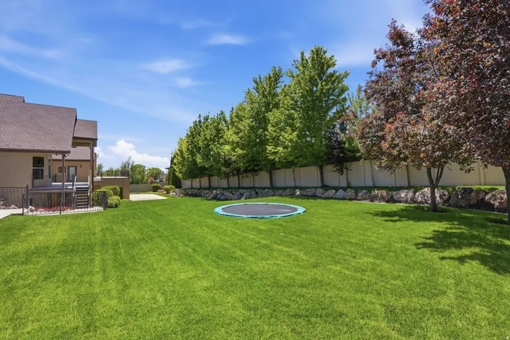 Expansive green lawn with mature trees and a private fence