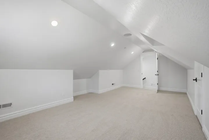 Carpeted bonus room featuring recessed lighting, a white painted interior, and sloped ceiling architecture