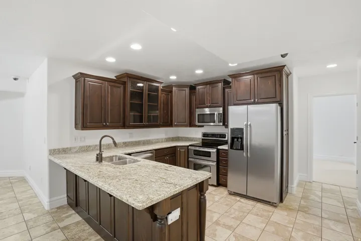 Kitchen featuring granite countertops, dark wood cabinetry, stainless steel appliances, and tile flooring