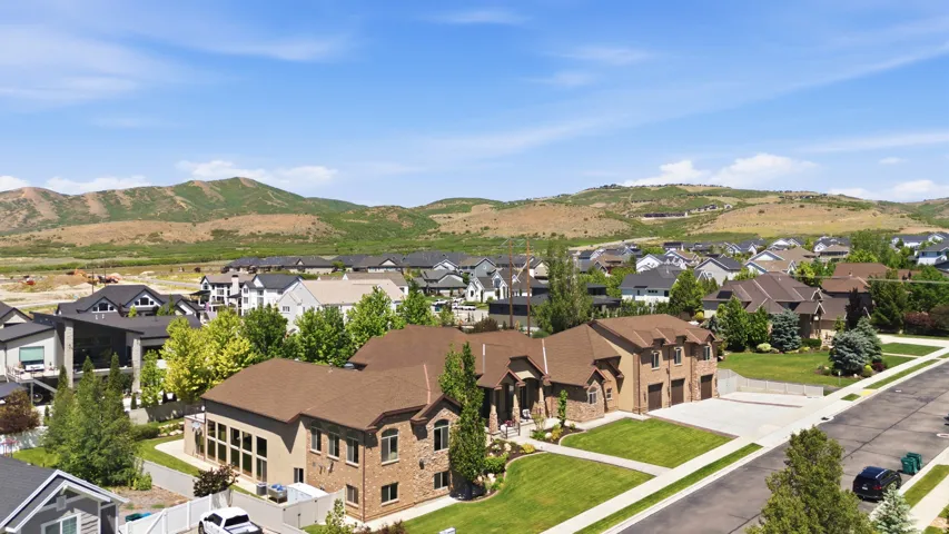 Expansive residence featuring a stucco and stone exterior, a multi-car garage, and a lush green lawn