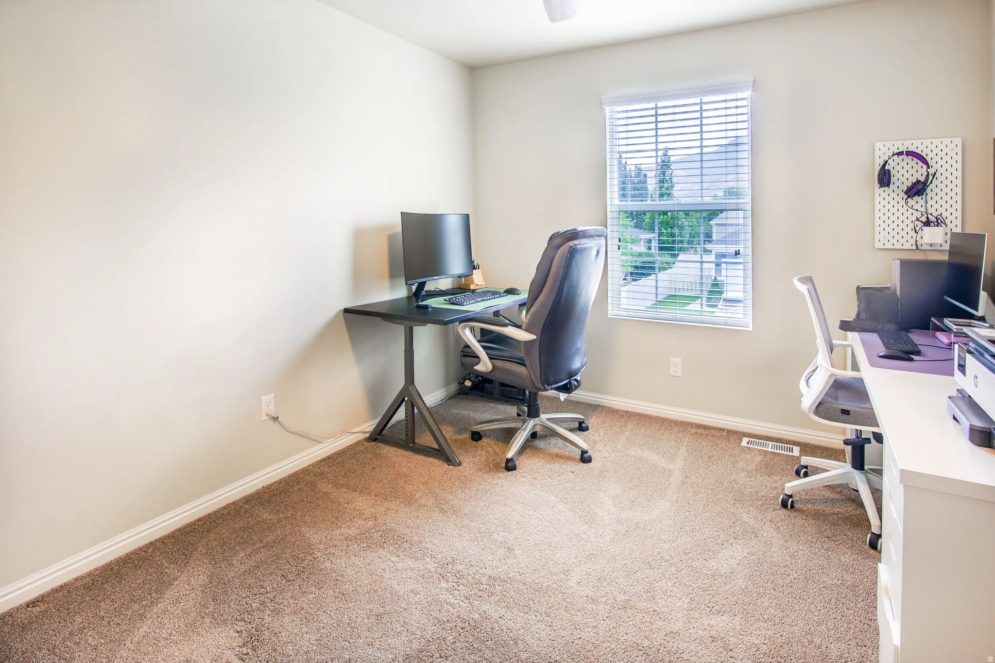 Carpeted room with a ceiling fan and window featuring white blinds