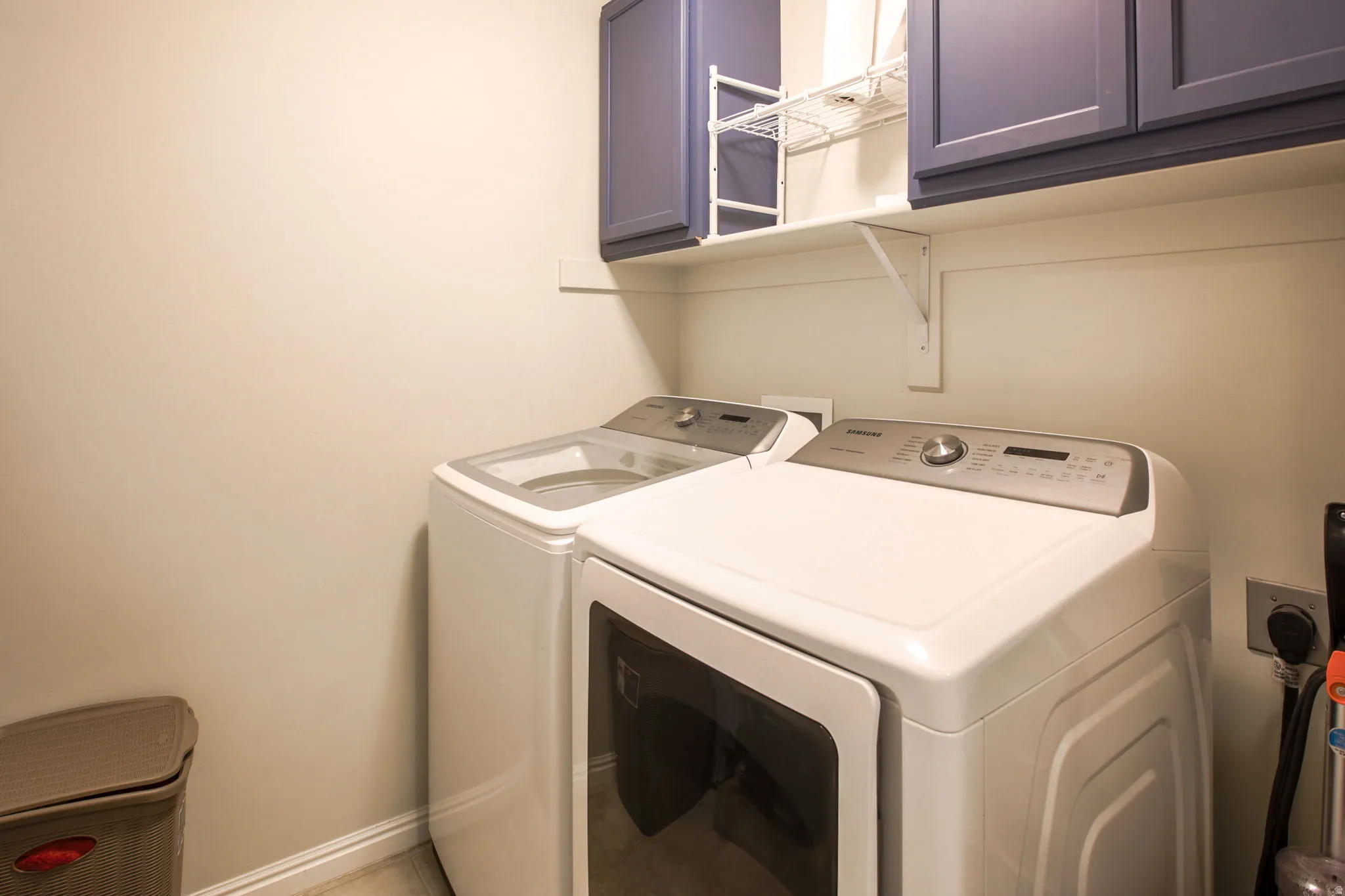 Dedicated laundry area featuring upper cabinetry, open shelving, and a wall-mounted shelf