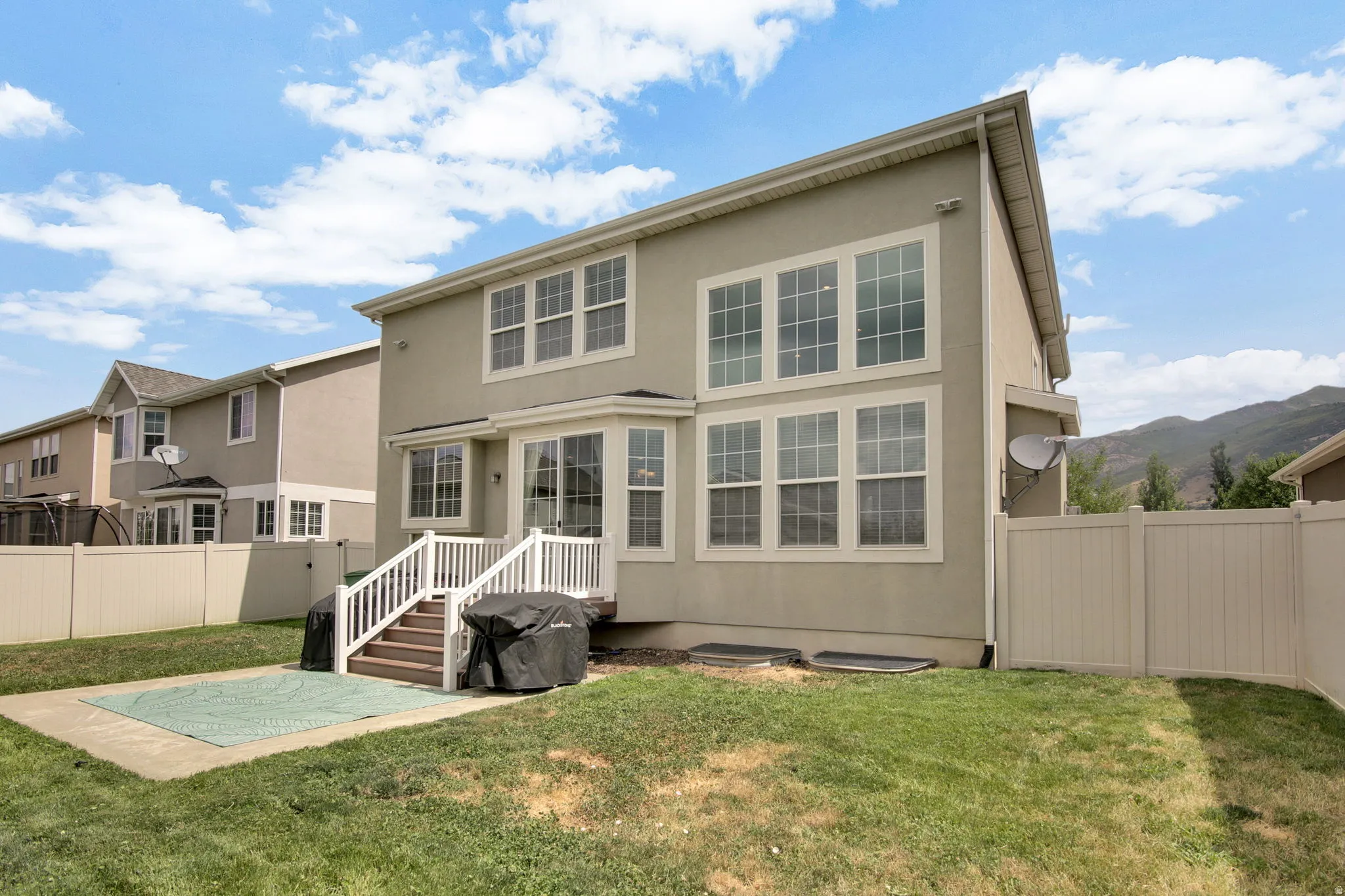 Rear exterior featuring a two-story stucco facade, a bay window, and a white deck with stairs