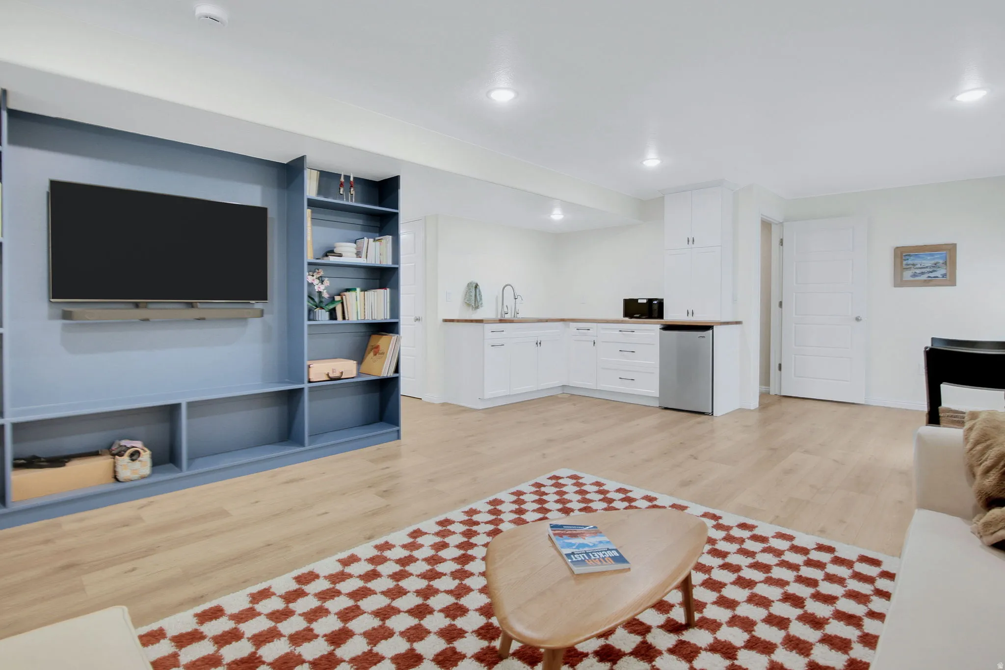 Open-concept living space featuring wood-finish flooring, a built-in media center with shelving, and recessed lighting