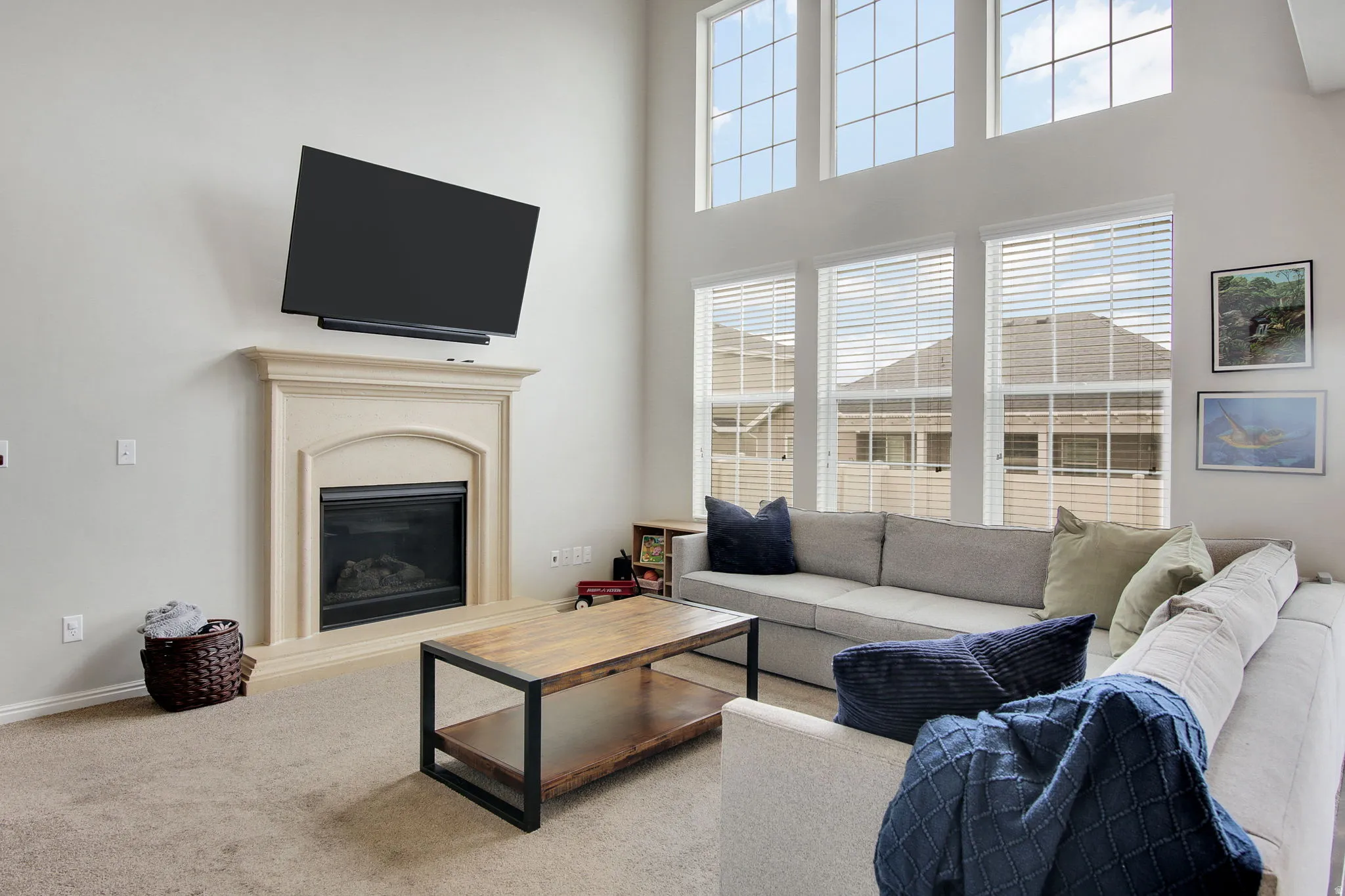 Living area featuring a floor-to-ceiling fireplace with an arched firebox, soaring vaulted ceilings, and a wall of windows with upper transom sections