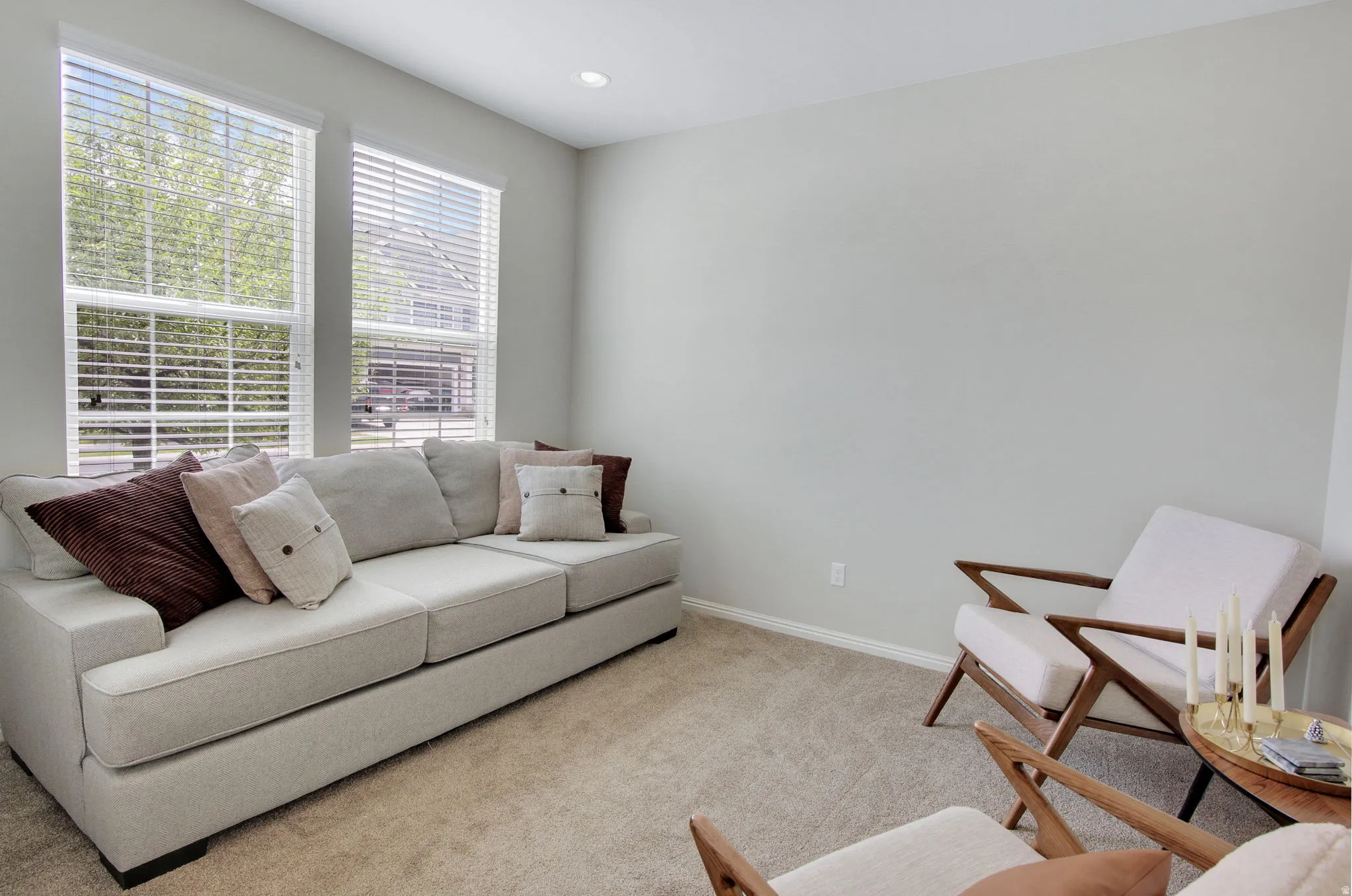 Bright living area featuring two large windows with blinds, recessed lighting, neutral wall tones, and carpet flooring