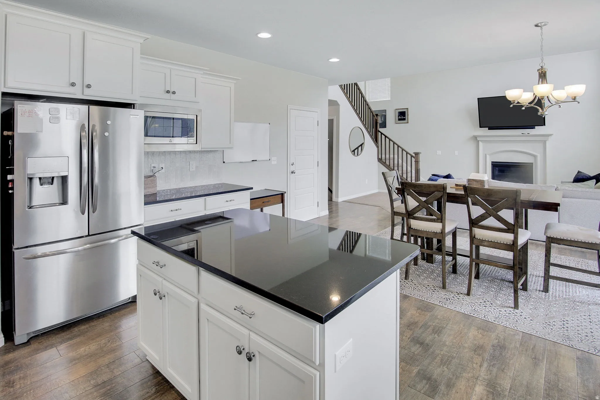 Kitchen featuring white cabinetry, stainless steel appliances, dark countertops, and wood-finish flooring