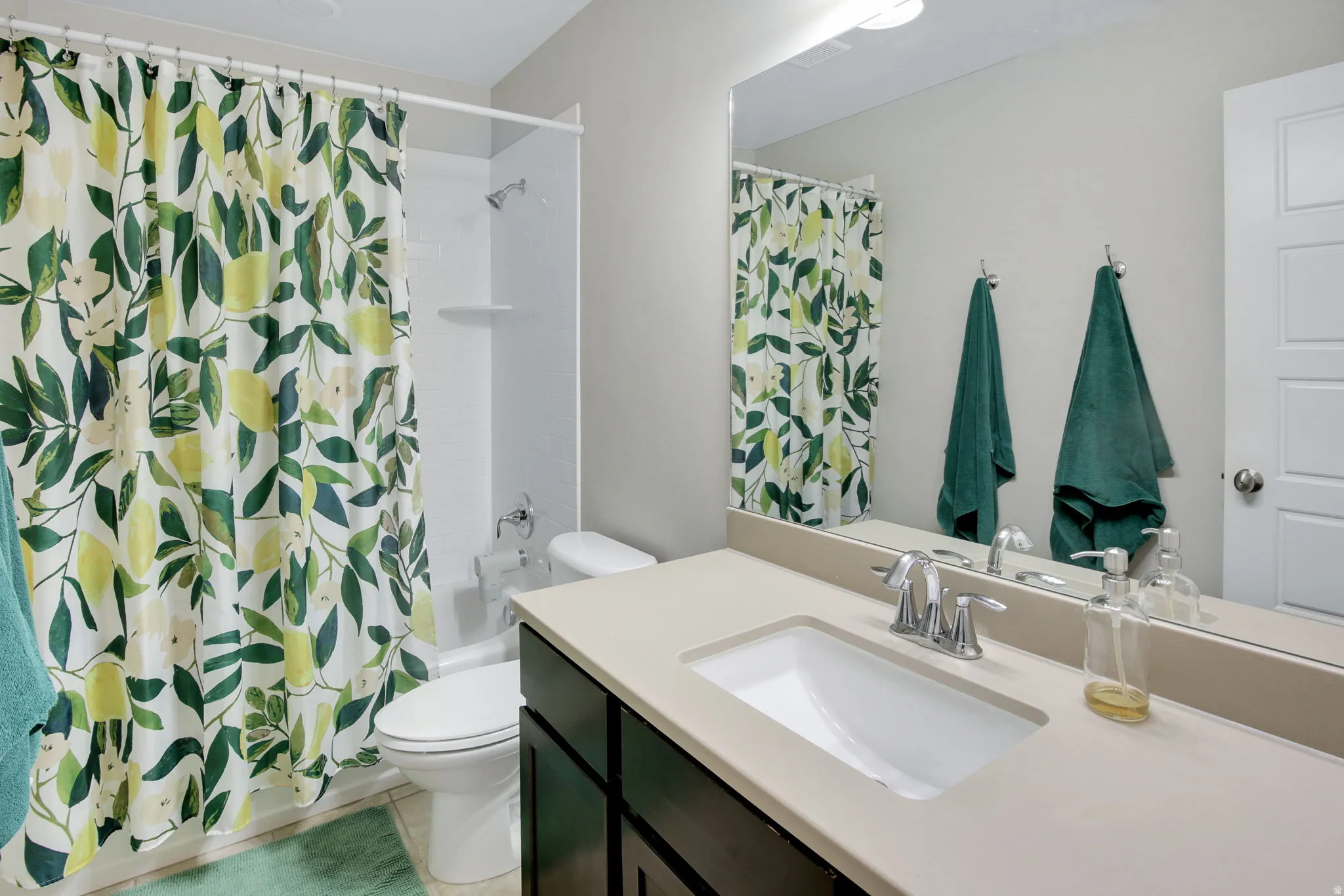 Full bathroom featuring a dark wood-finish vanity with a light-toned countertop, an integrated rectangular sink, and a chrome faucet