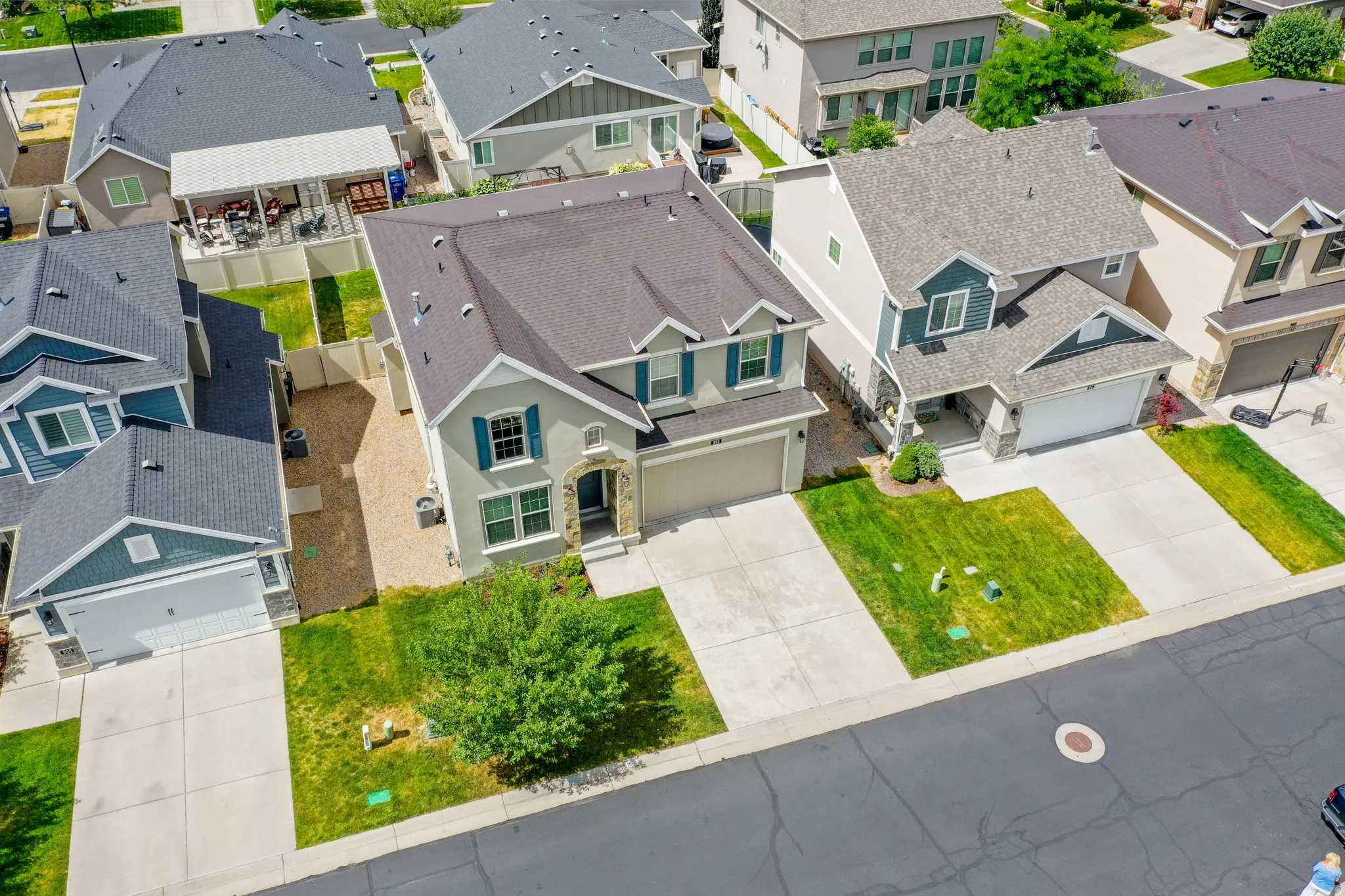 Two-story residence featuring a two-car garage, stone and stucco facade, decorative window shutters, and a well-maintained front lawn