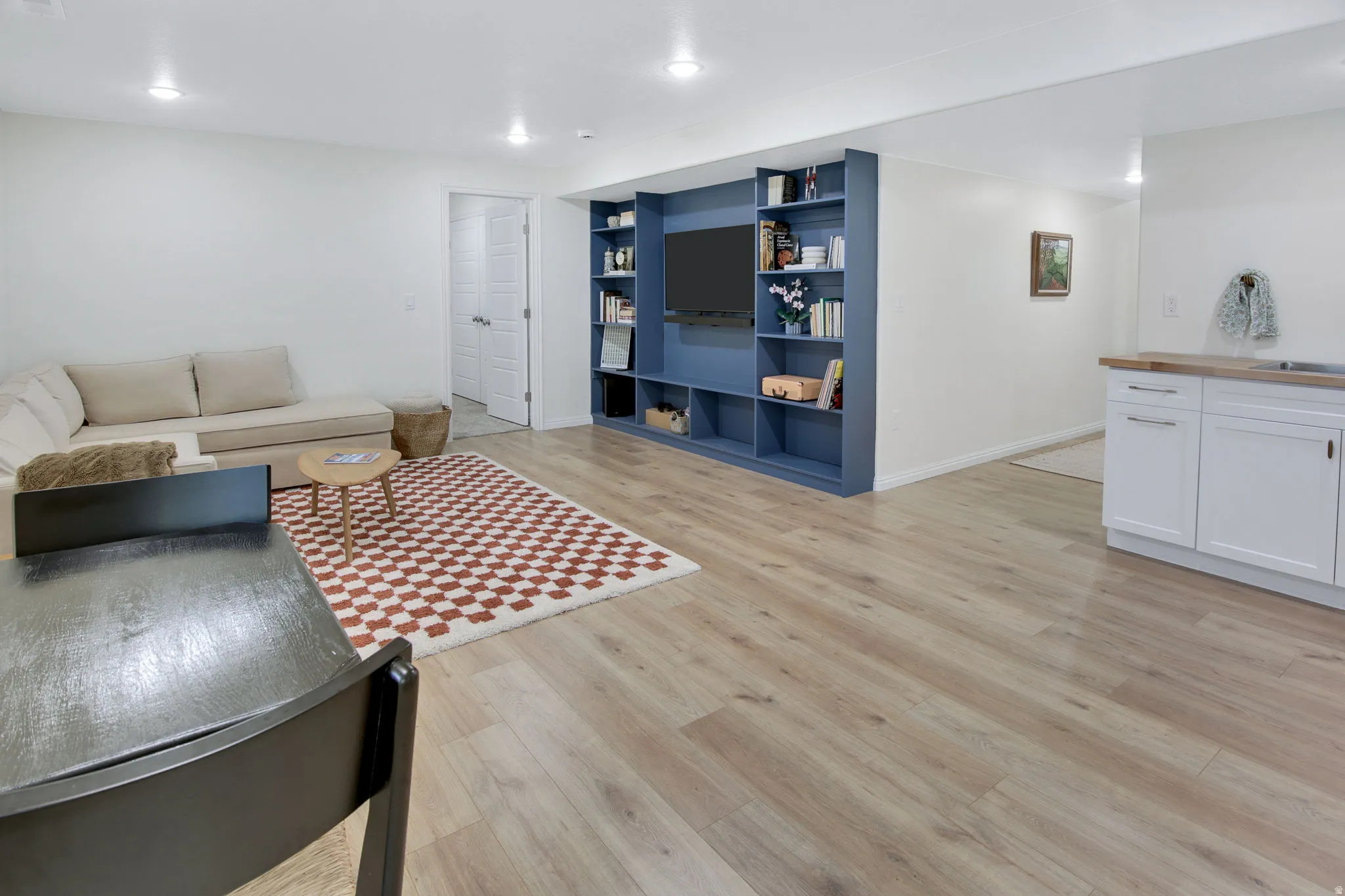 Open concept living area featuring wood-finish flooring, recessed lighting, a built-in media center with shelving, and a wet bar with white cabinetry and a wood countertop