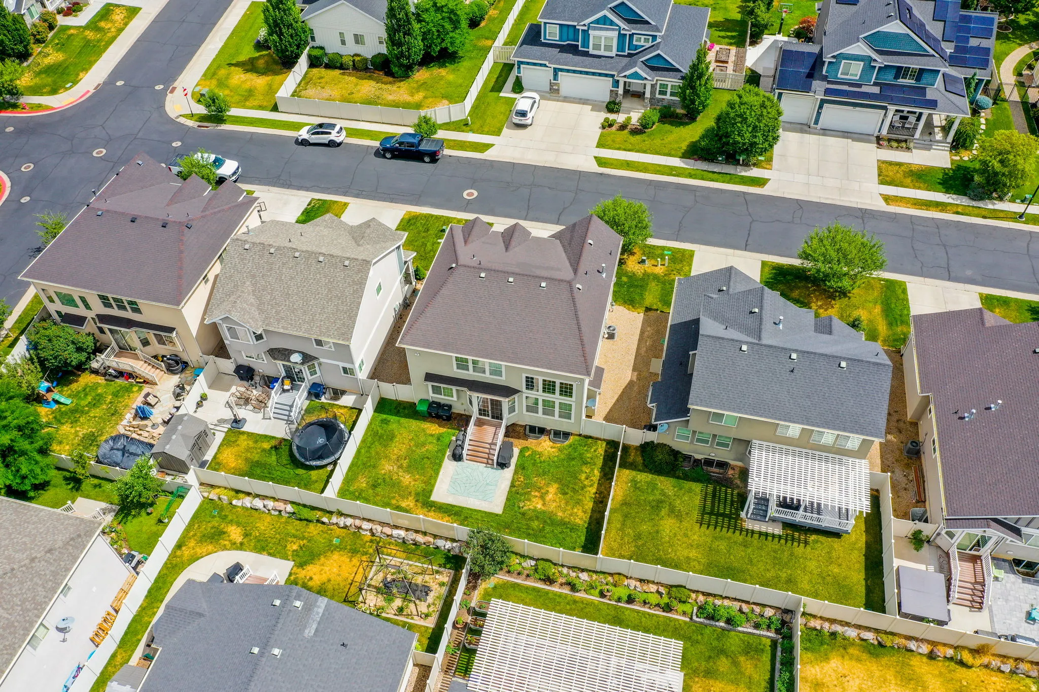 Modern residential property with a multi-level exterior, featuring a gray shingle roof, light-colored siding, and a fenced backyard with green lawn