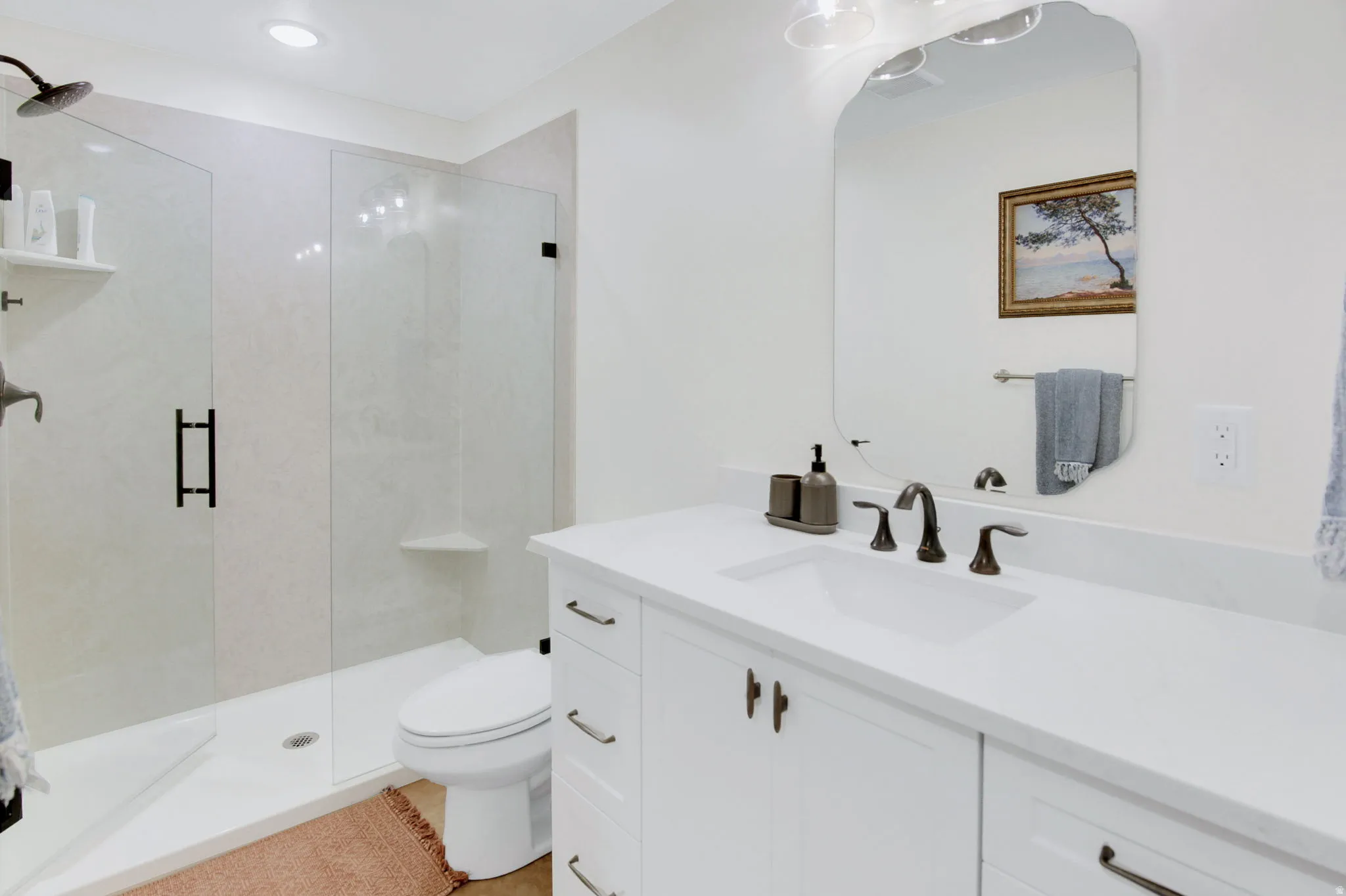 Bathroom featuring a glass-enclosed shower with a black rain shower head, white tiled walls, and a built-in corner shelf