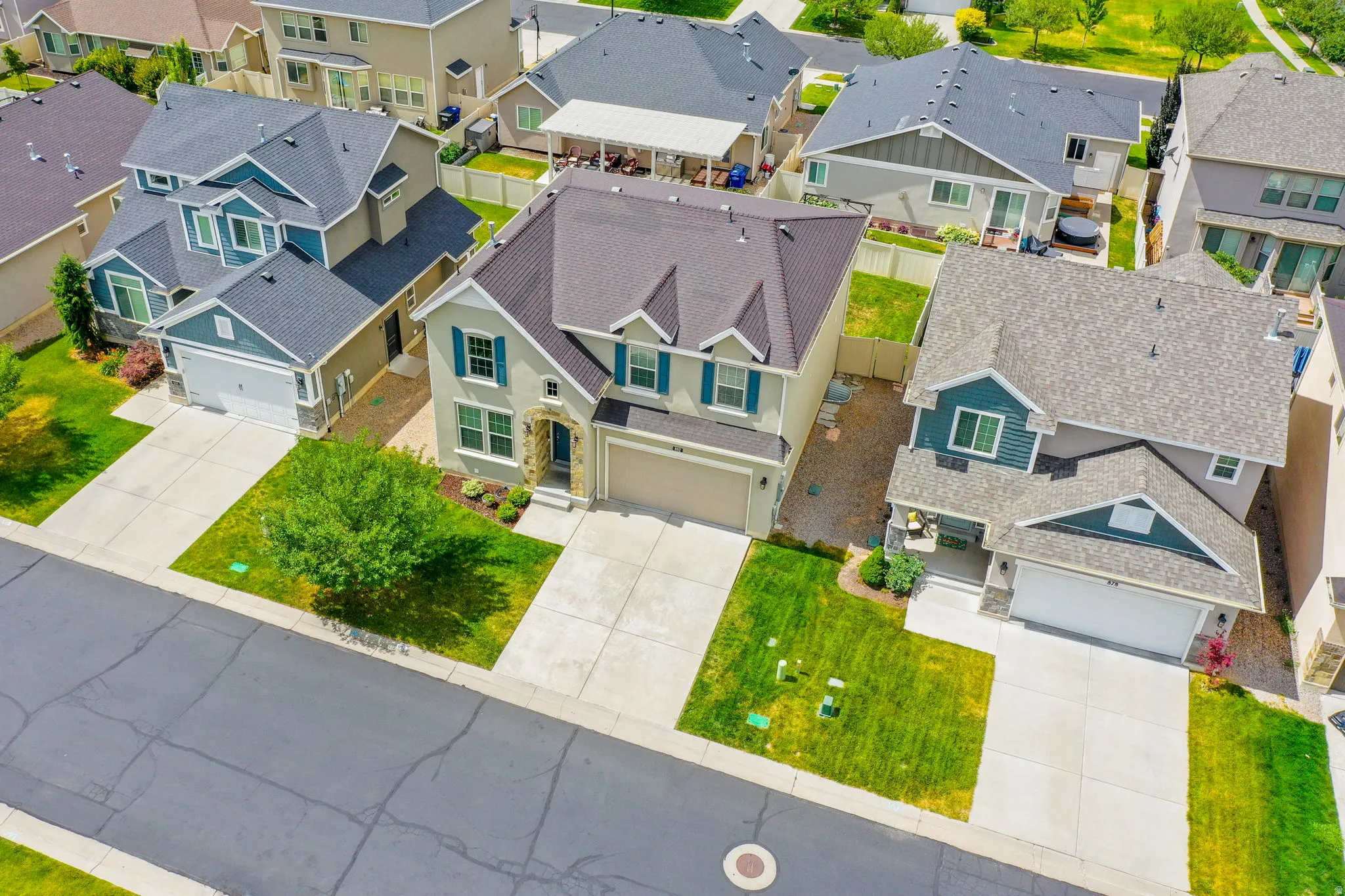 Two-story residence with a light-colored stucco exterior, stone accents, and dark roofing