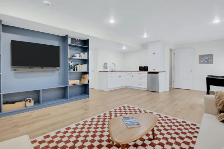Open-concept living space featuring wood-finish flooring, a built-in media center with shelving, and recessed lighting