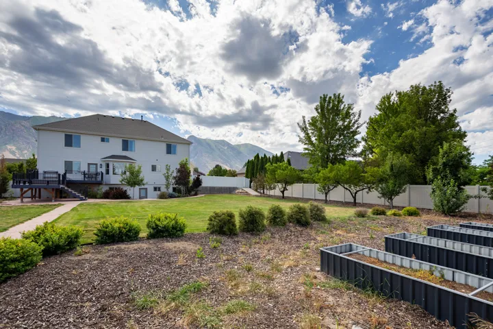 Expansive backyard featuring a large green lawn, mature trees, and a concrete paver pathway