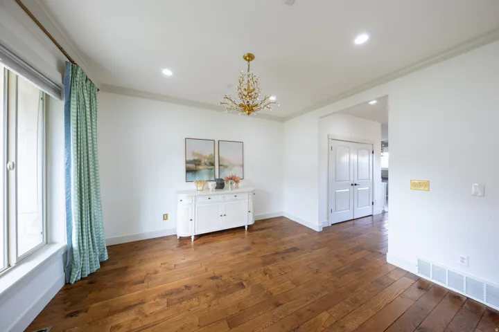 Spacious room featuring wood-finish flooring, a contemporary chandelier, recessed ceiling lighting, crown molding, and white baseboards
