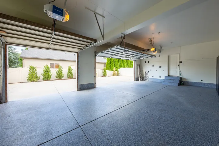 Spacious garage featuring a durable epoxy floor coating, two automatic garage door openers, and direct entry to the interior