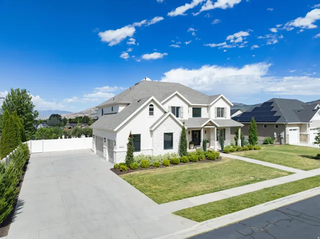 White stucco and stone facade residence featuring a covered entry, multiple gables, and a two-car garage
