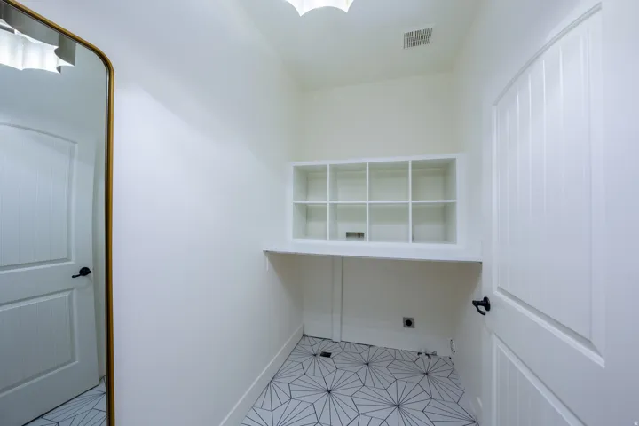 Built-in shelving with cubby storage, white countertop, geometric tile flooring, and white paneled doors