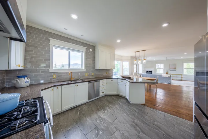 Modern kitchen featuring white cabinetry, a gray subway tile backsplash, dark countertops, and stainless steel appliances