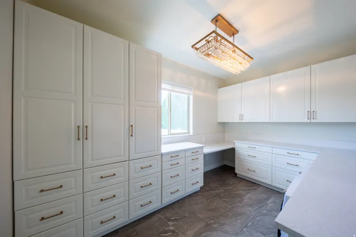 Spacious room featuring extensive white cabinetry with varied storage options, including full-height pantry-style units and multiple drawers