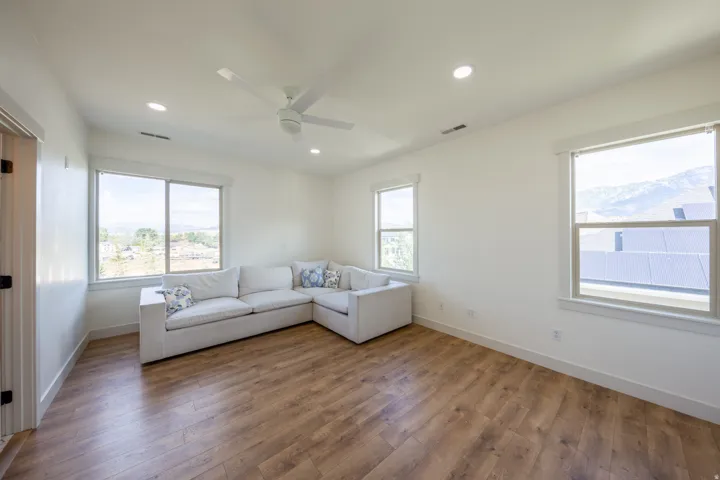 Spacious room featuring wood-finish flooring, ample natural light from multiple windows, recessed lighting, and a ceiling fan
