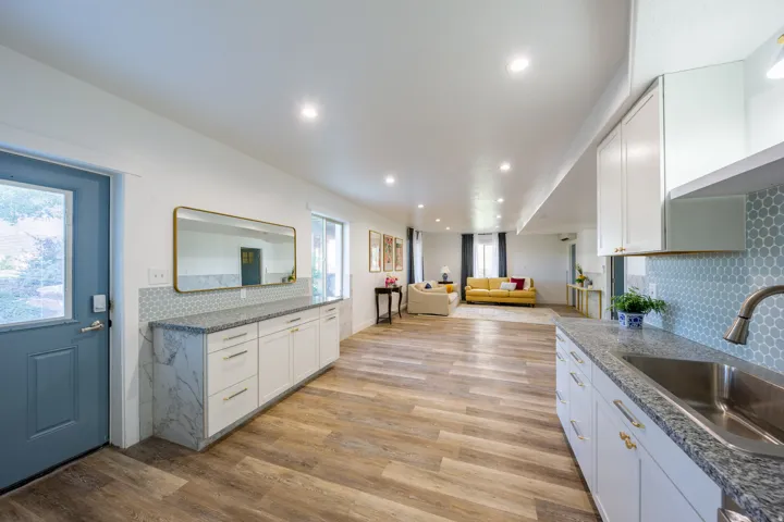 Expansive interior featuring wood-finish flooring, recessed lighting, and a kitchen area with white cabinetry and a stainless steel sink