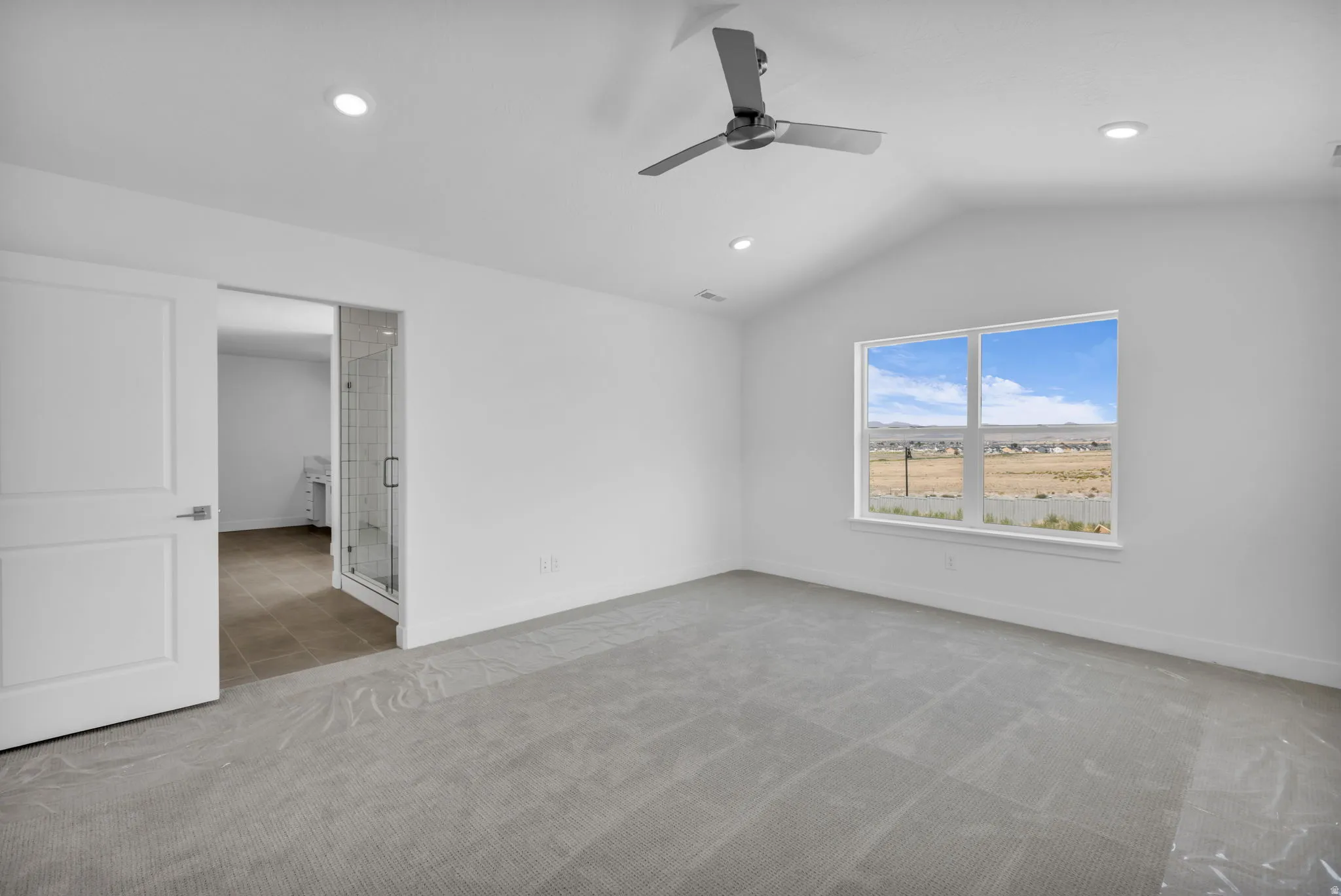Vaulted ceiling in primary bedroom with view to primary bathroom.