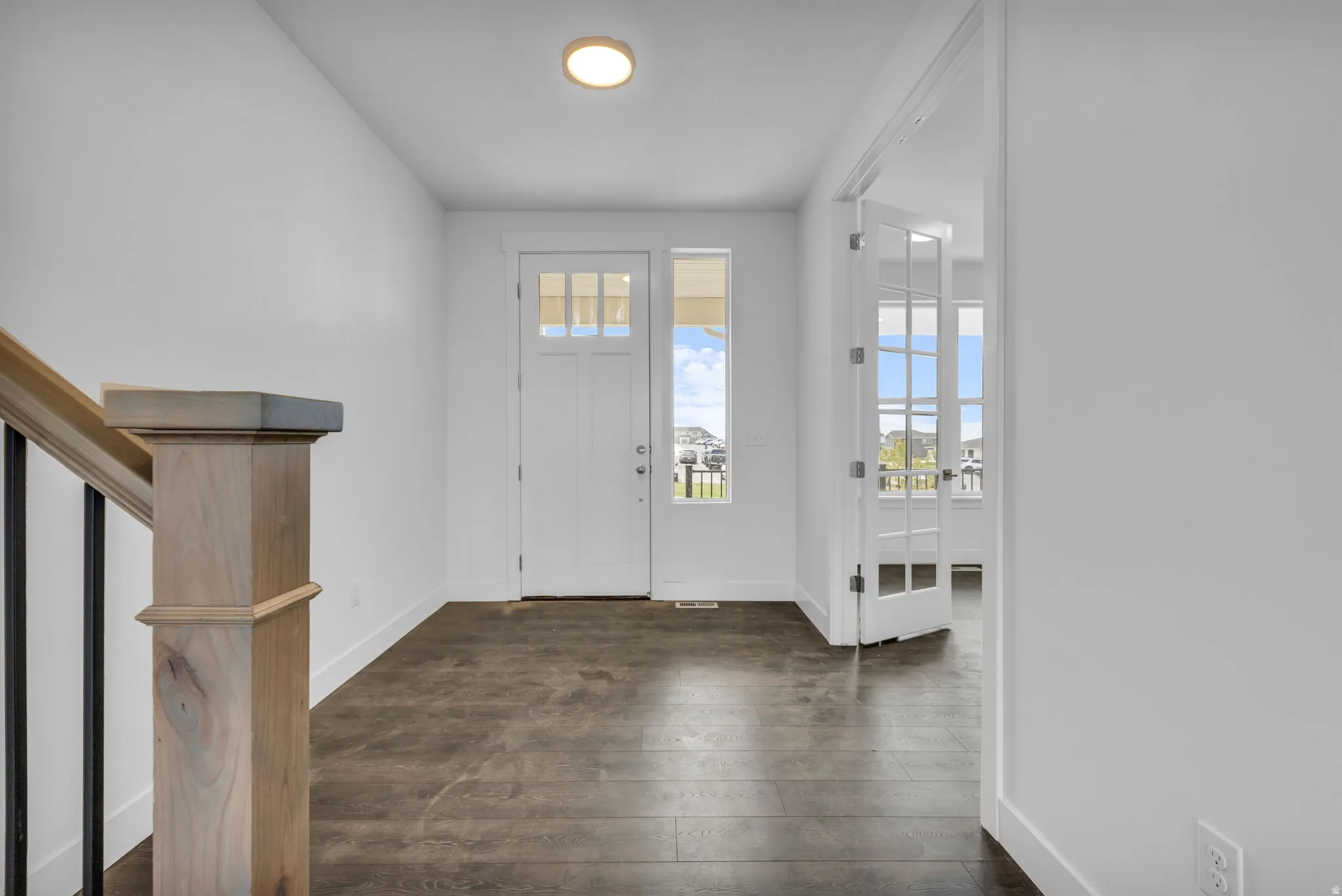 Entry foyer featuring a craftsman-style 8' tall front door with transom window and sidelight.  View of double French doors to the flex space off the entry.