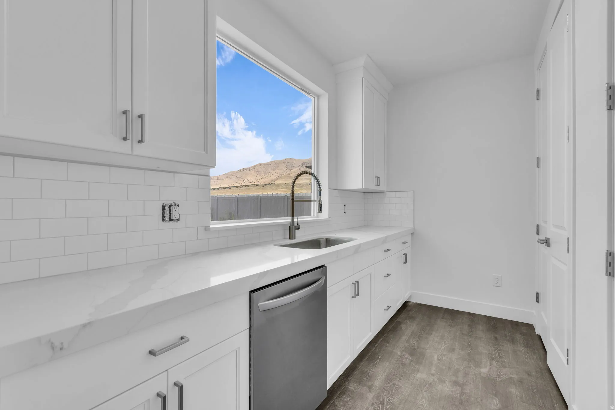 Butler's pantry featuring white shaker cabinetry, stainless steel dishwasher, white subway tile backsplash, Quartz countertops and tons of cabinetry with two double door shelved pantries.