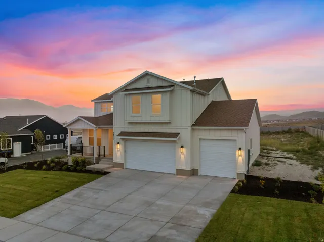 Farmhouse style two-story home featuring a three-car garage, and a large covered porch. View from the southeast corner of property.