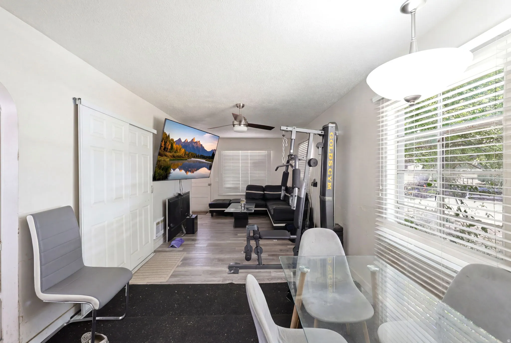 Open concept room featuring wood-finish flooring, white walls, and a ceiling fan