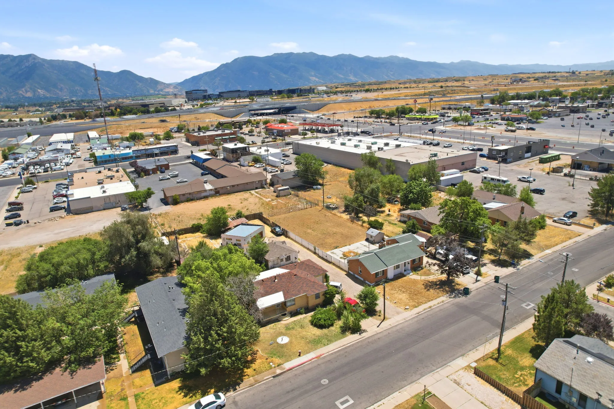 Aerial view showcasing a mix of residential and commercial properties with mountainous terrain as a distant backdrop