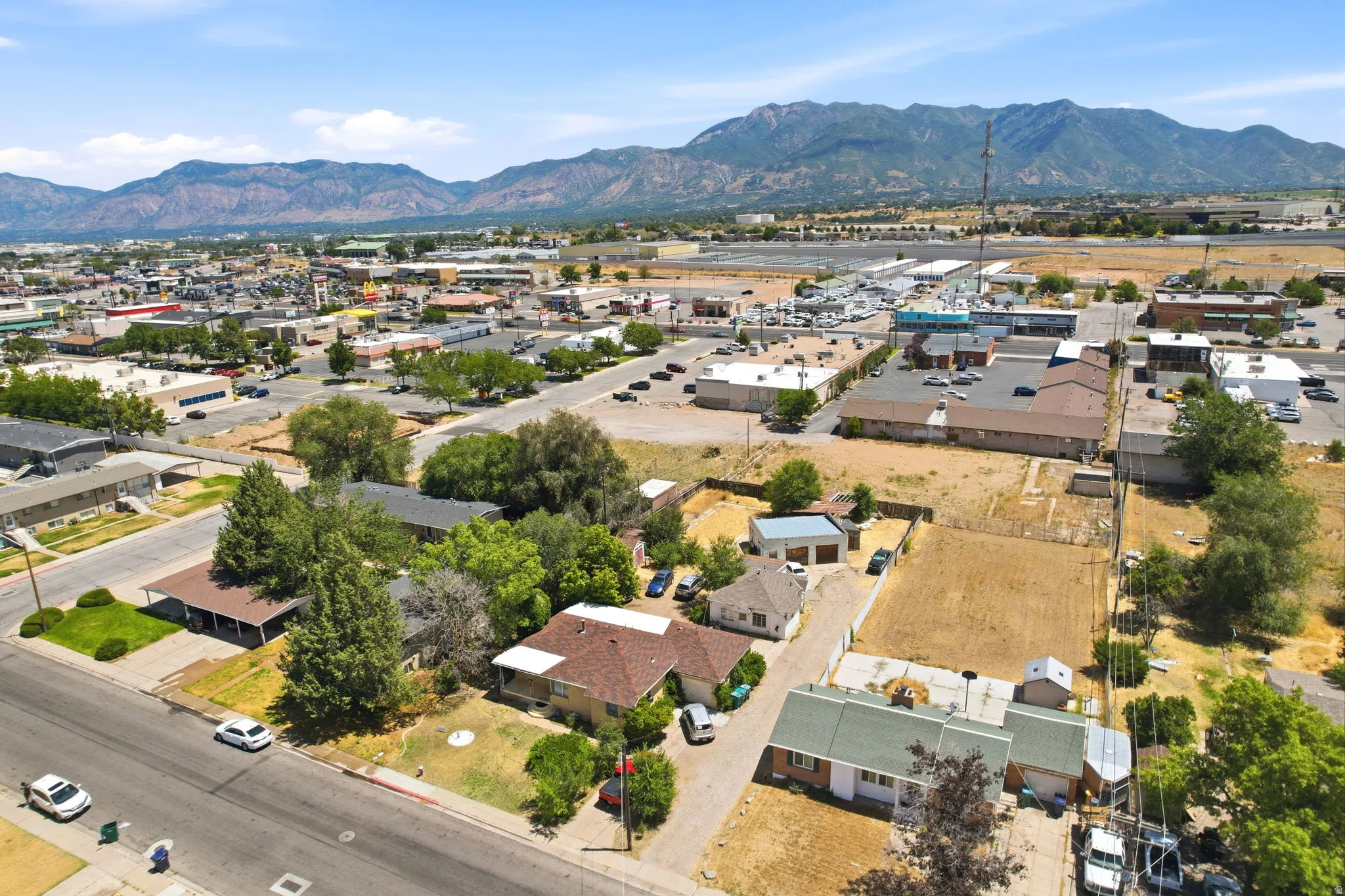 Aerial view of a residential street with mature trees and a distant mountain range