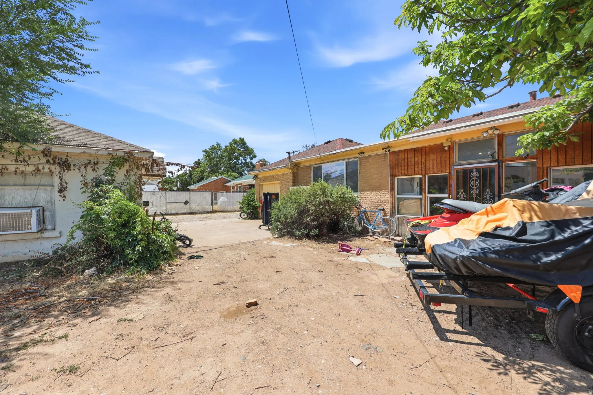 Expansive rear yard area featuring a detached structure, concrete patio, and mature trees