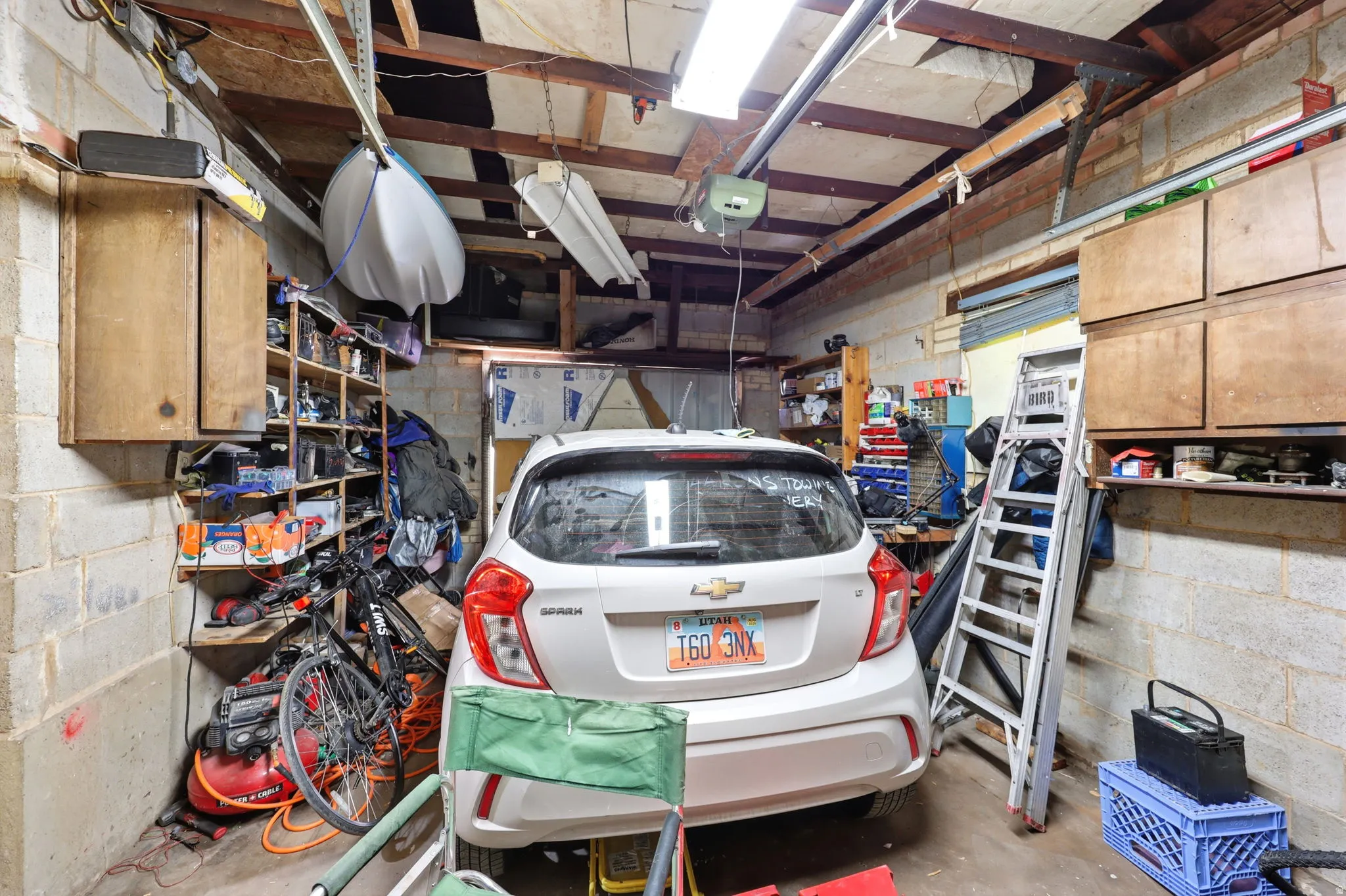 Garage space featuring concrete block walls and exposed wood beam ceiling