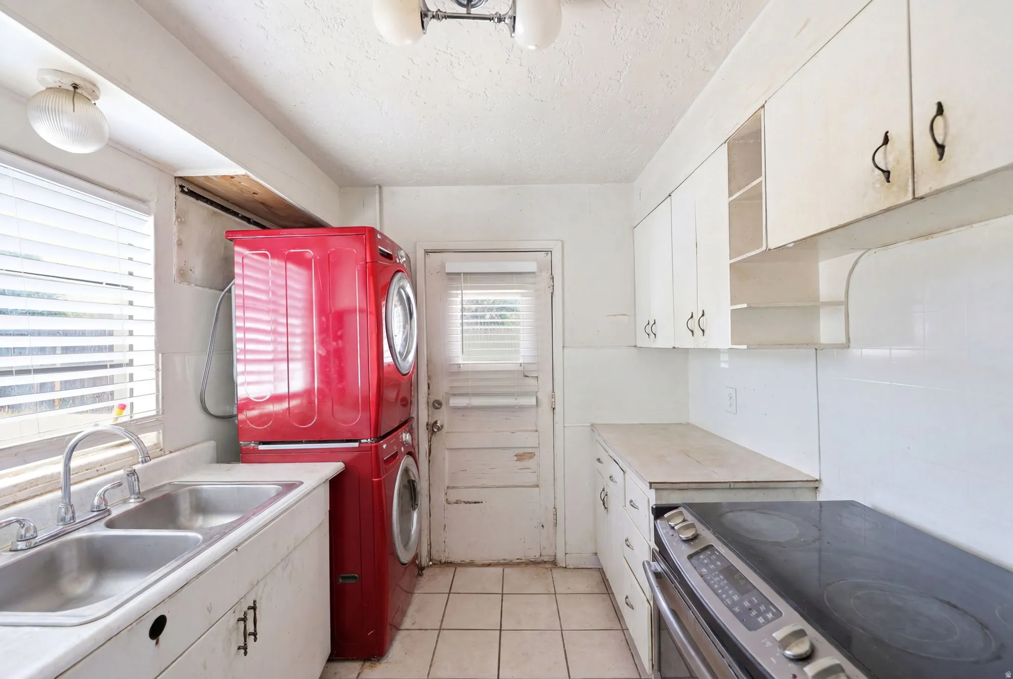 Kitchen space featuring white cabinetry, a double basin stainless steel sink, and a built-in electric range with a flat cooktop