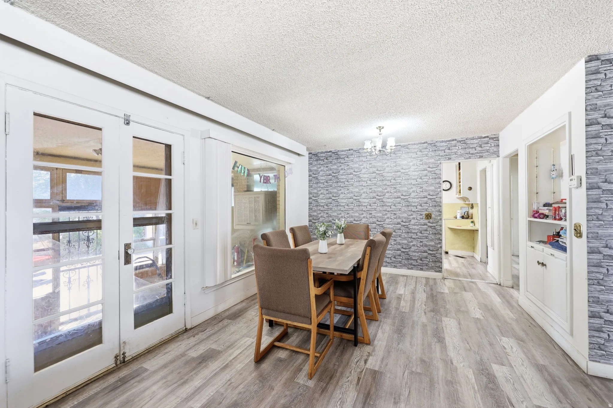 Dining area featuring light wood-finish flooring, a decorative stone-patterned accent wall, and a multi-light chandelier