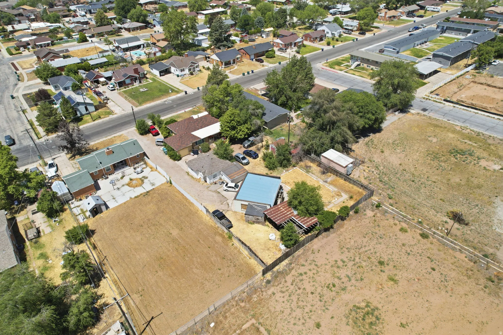 Aerial perspective showcasing a residential property with a partial fence perimeter, mature trees, and a detached structure