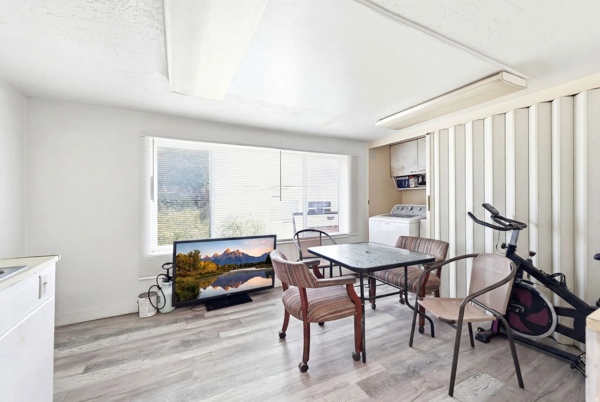 Versatile space featuring wood-finish flooring, a large window, built-in cabinetry, and a utility area with a washing machine