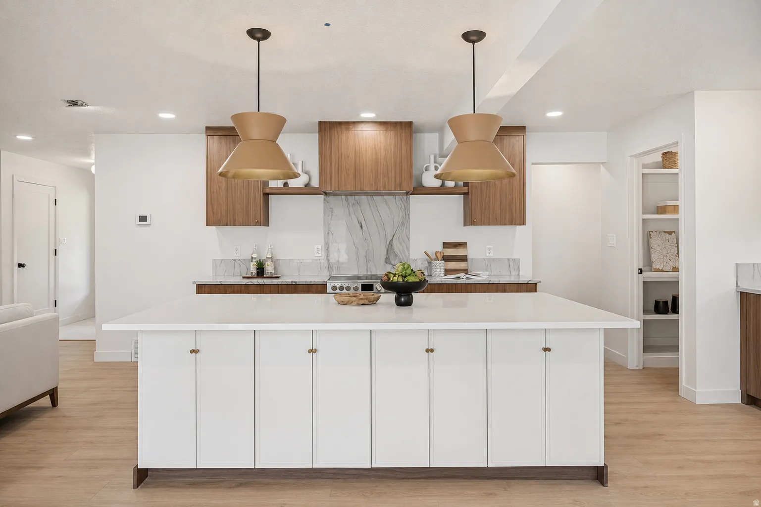 Kitchen featuring a large central island with white cabinetry, wood-finish flooring, recessed lighting, and two pendant light fixtures