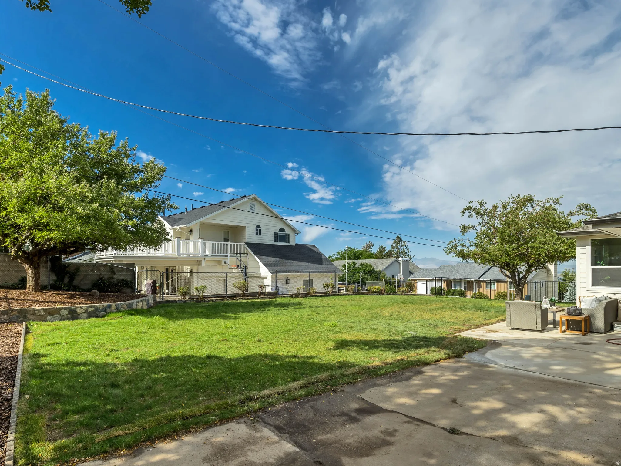 Expansive backyard featuring a large grass area, mature trees, a multi-level deck, and a concrete patio