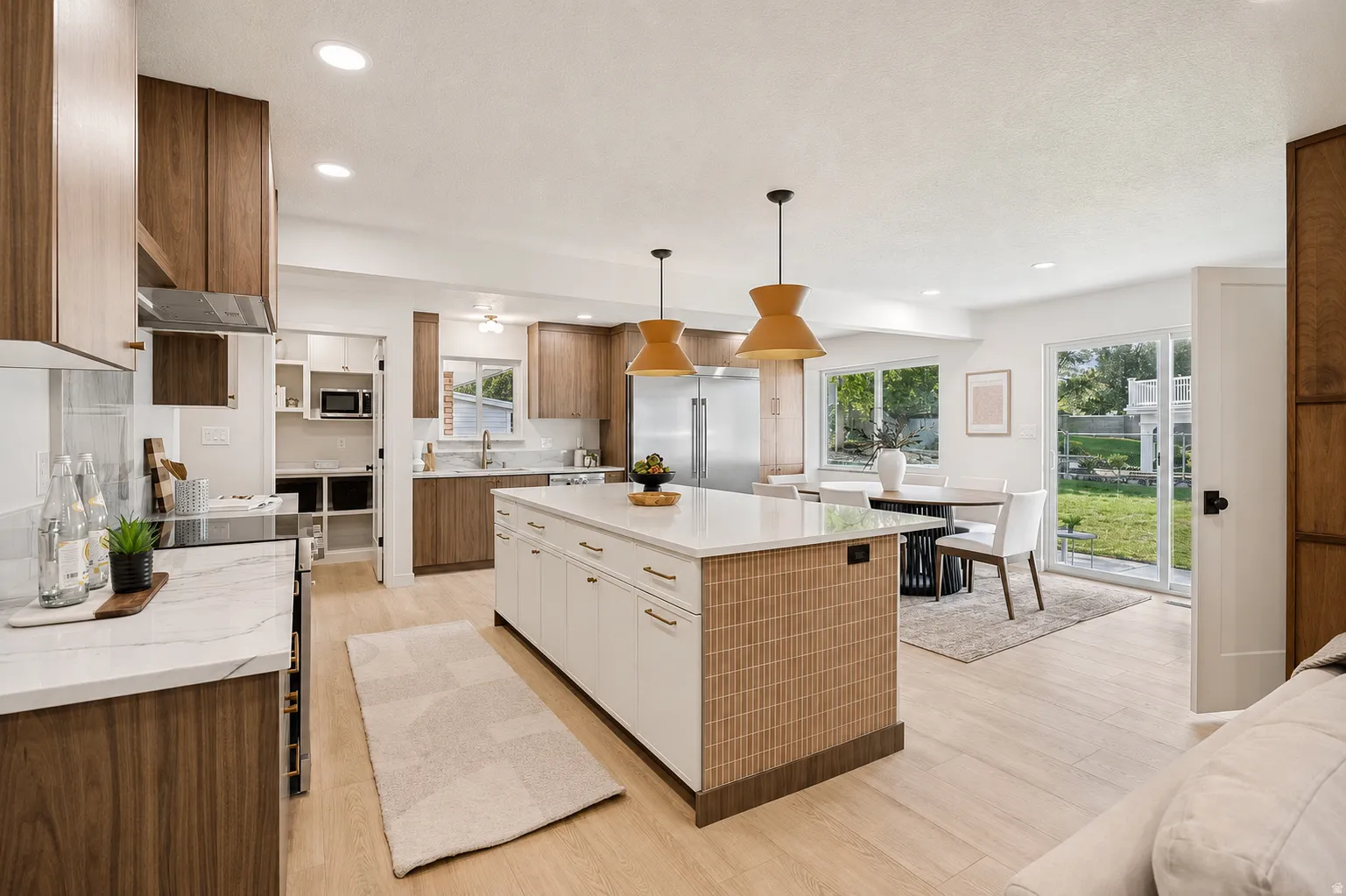 Open-concept kitchen featuring an oversized island with white cabinetry and a textured wood-finish facade