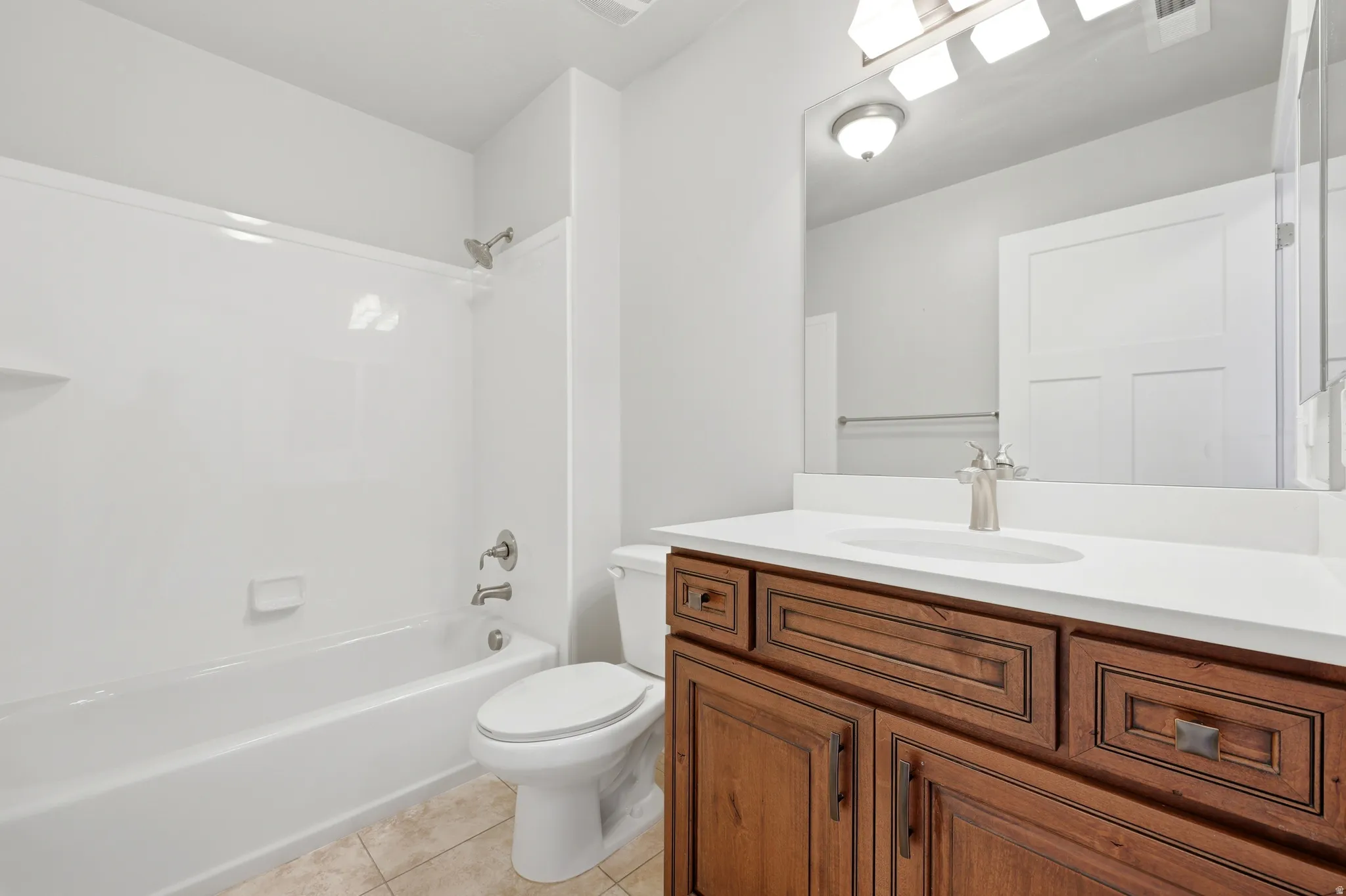 Bathroom featuring a wood-finish vanity with a white countertop and undermount sink
