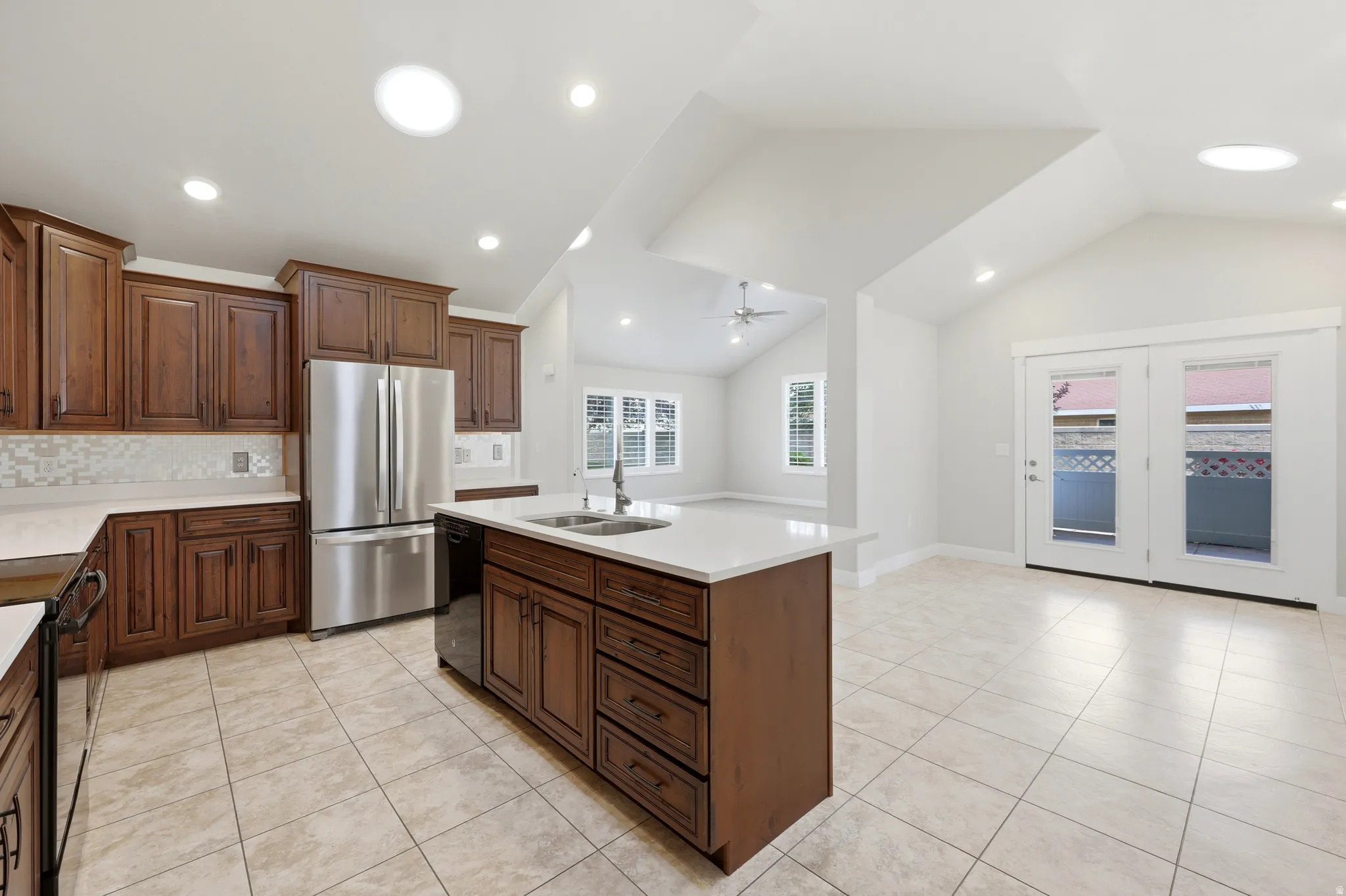 Kitchen featuring wood cabinetry, stainless steel appliances, a center island with sink, and tile flooring
