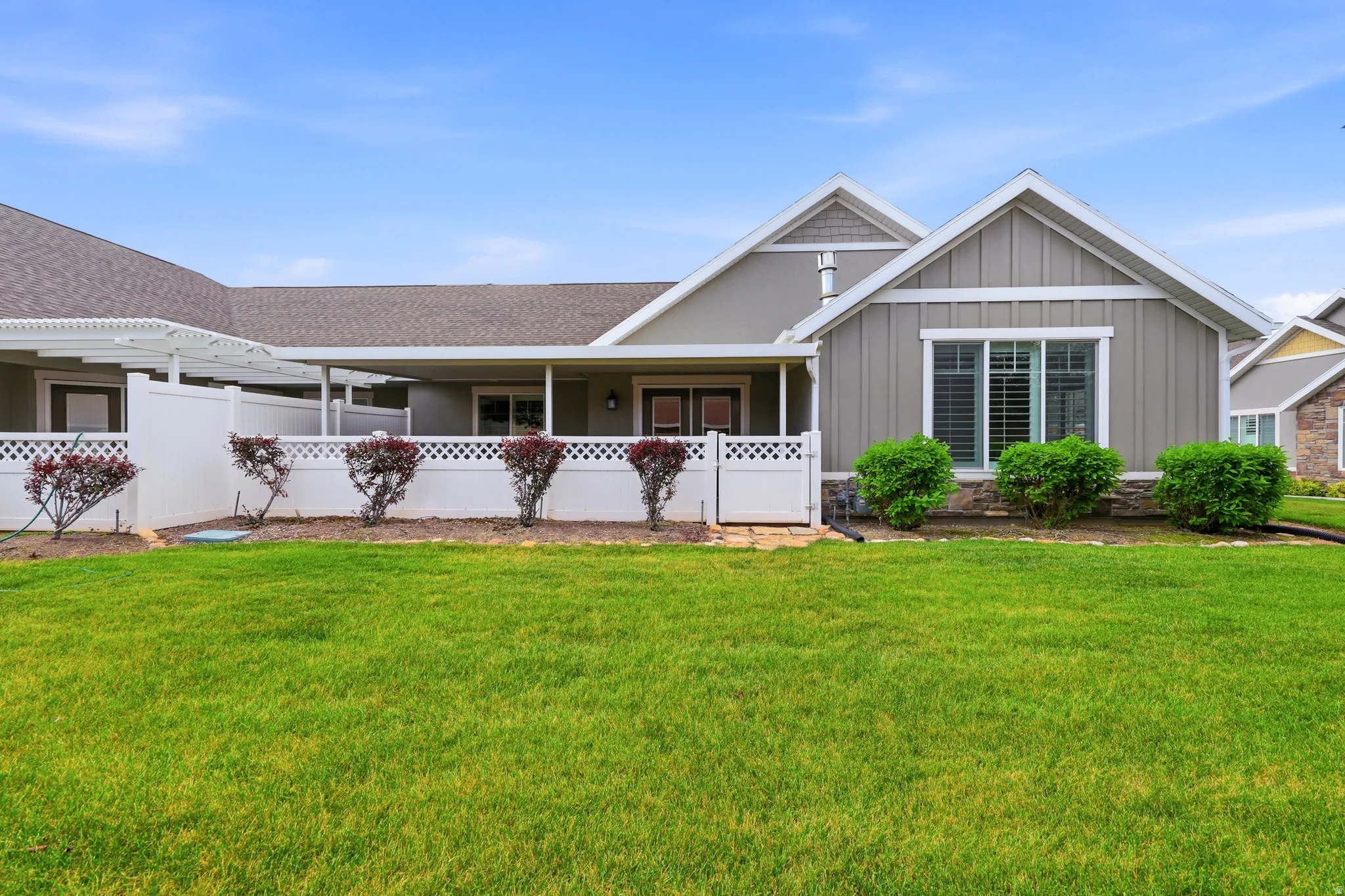 Expansive green lawn with a white lattice-top fence and mature landscaping